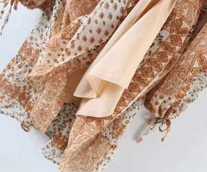 Détail de robe bohème à motif paisley avec poignets noués et volants superposés