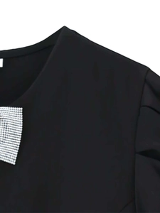 Détail de la robe noire avec nœud en strass argentés et manches bouffantes