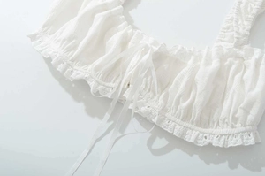 Détail du haut en dentelle blanche avec volants et broderie aux rubans délicats
