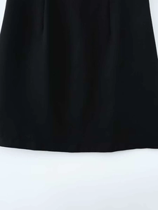 Détail d'une mini robe noire tissée avec plis décoratifs et ourlet aux finitions soignées