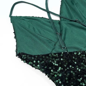 Detail of dark green dress showing crisscross satin straps and dense sequin textures