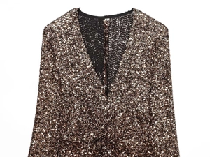 Close-up of the deep V-neckline and shiny sequins on the gold evening dress
