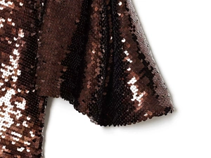 Detailed macro view of caramel brown sequins on a shimmering stylish party dress fabric
