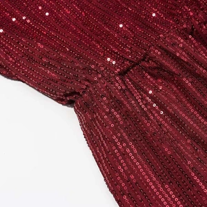 Detailed close-up of wine red sequins on deep V-neck dress with shiny vertical texture