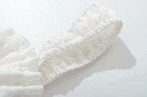 Détail d'une bretelle en dentelle blanche avec bords élastiques plissés et tissu jacquard