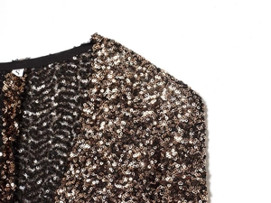 Detail of shimmering champagne gold sequins sewn on black fabric with elegant V-neckline