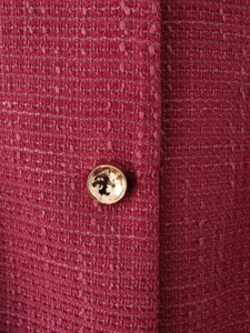 Dettaglio macro del tessuto in tweed magenta con bottone in metallo dorato decorato