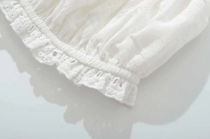 Détail du haut court blanc avec des plis élastiques et une broderie ajourée délicate