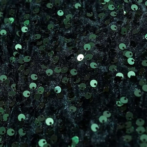 Close-up of deep green sequins stitched on soft fabric for party mini dresses