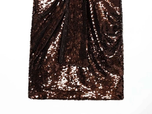 Macro shot of shimmering caramel sequin fabric with detailed pleats on a mini dress