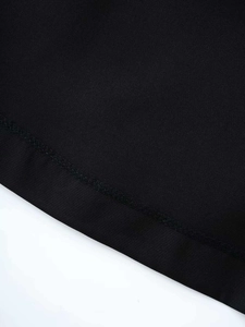 Gros plan d'une robe noire courte montrant les coutures doubles et la texture du tissu