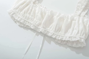 Détails d'un haut blanc avec smocks, bordure en dentelle délicate et tissu texturé