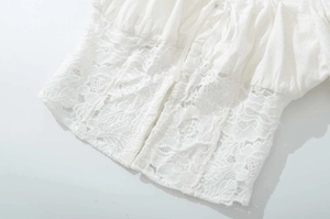Detail of white lace stitching on slim-fit top featuring delicate floral embroidery fabric