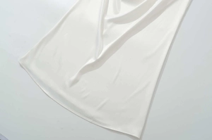 Vue détaillée du tissu en satin blanc lisse et de la couture de l'ourlet de la robe