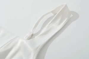 Détail de la boucle en métal réglable et de la bretelle en satin blanc lisse de la robe