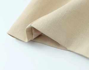 Nahaufnahme von beigem Blazerstoff mit detaillierter Textur und glattem Innenfutter