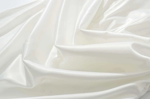 Vue détaillée du luxueux tissu en satin blanc au lustre perlé et drapé élégant de la robe
