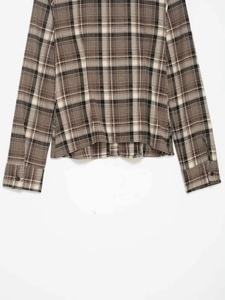 Detail of plaid long-sleeve shirt cuffs and textured fabric hem on a white background