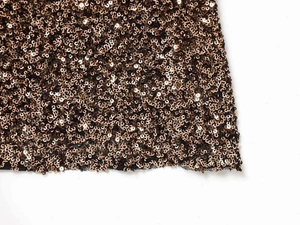 Close-up of sparkling bronze gold sequins on black mesh fabric for v-neck dress