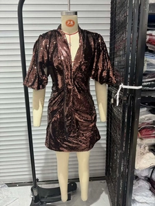 Close-up of sparkling caramel brown sequins and pleated fabric detail on mini dress