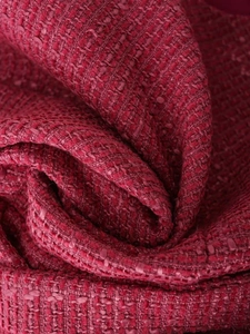 Vista macro del tessuto in tweed rosso che mostra la trama intrecciata e i dettagli ricchi