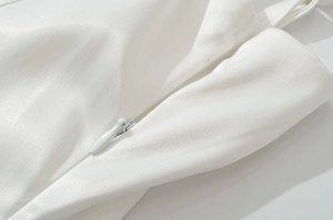 Détail de la fermeture éclair invisible sur une robe longue en satin blanc tissé