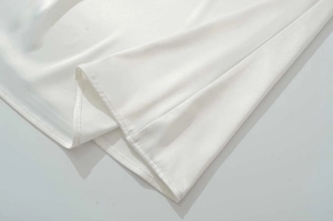 Gros plan détaillé montrant l'ourlet à double couture sur le tissu en satin blanc