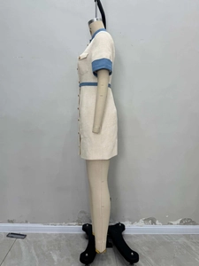 Détail d'une robe en tweed avec boutons dorés et bordures contrastées à la taille