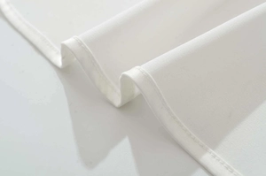 Gros plan sur les coutures de qualité et l'ourlet roulé de la robe longue en satin blanc