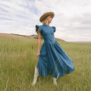 Close-up of denim dress with ruffles sleeves, single-breasted buttons and waist detail