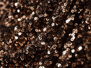Macro view of high-density bronze sequins sewn on fabric showing metallic texture