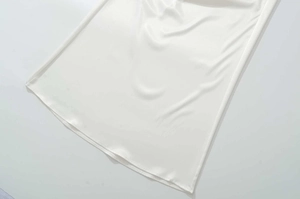 Vue détaillée en gros plan du tissu satiné blanc montrant sa texture lisse et brillante