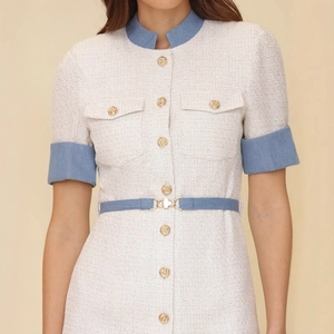 Détail d'une robe en tweed beige avec des bordures bleues contrastées et des boutons dorés