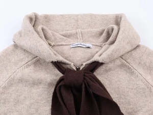 Dettaglio felpa in maglia beige con fiocco marrone e chiusura a zip in metallo resistente
