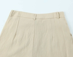 Detailaufnahme der beigen Leinenhose mit Gürtelschlaufen und plissiertem Taillendesign