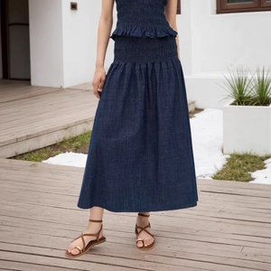 Detailaufnahme des dunkelblauen High-Waist Denim-Maxirocks mit Lagenfalten