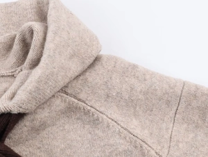 Dettaglio ravvicinato della scollatura della felpa in maglia beige e del tessuto