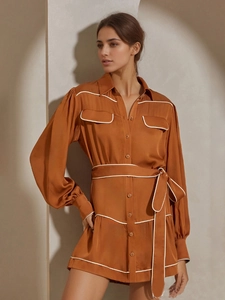 Détail de la robe en satin caramel avec liseré blanc et ceinture nouée à la taille