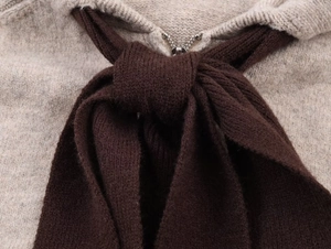 Dettaglio felpa in maglia avena con zip in metallo e fiocco decorativo marrone