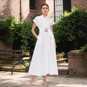 Dettaglio vita di un vestito lungo bianco con fibbia dorata e design aderente
