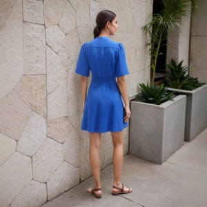 Detail of the blue A-line dress featuring a V-neckline, waist tie, and hidden back zipper