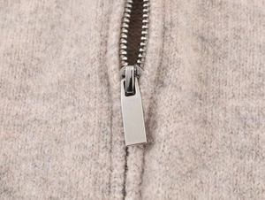 Dettaglio macro del tessuto a maglia beige e cerniera in metallo argentato sulla felpa