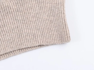 Dettaglio ravvicinato della trama in maglia a coste di una giacca beige con cappuccio