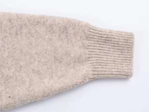 Dettaglio macro dei polsini a costine su un cardigan in maglia con cappuccio beige