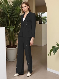 Detail of black slim-fit blazer and wide-leg pants with contrast white button accents