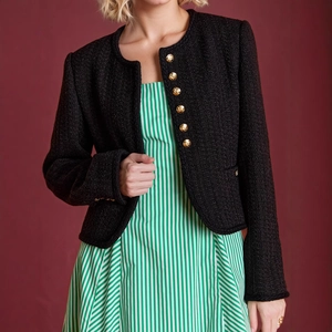Detail der klassischen schwarzen Tweed-Strickjacke mit goldenen Knöpfen und Strukturstoff