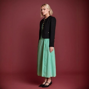 Detailaufnahme der Tweedjacke mit goldenen Knöpfen und gestreiftem Maxikleid