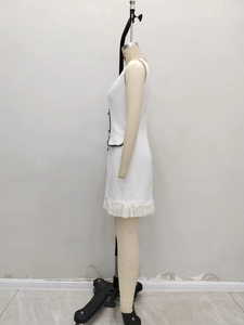 Détail d'une robe blanche sans manches avec bordure noire et ourlet à franges