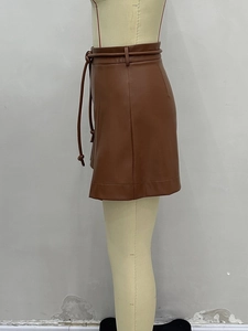 Détail de la mini-jupe en cuir PU marron montrant les coutures et la ceinture à nouer