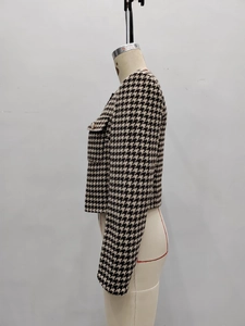 Detail of houndstooth tweed jacket featuring metallic buttons and flap pocket texture